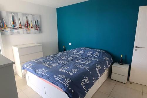 une chambre avec un lit avec un mur bleu dans l'établissement Beau T3 - Meublé classé 3*- Vue dégagée sur Marina, à Canet