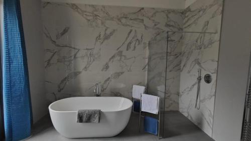 a bathroom with a white tub and a marble wall at Villa Giordana in Casalborgone