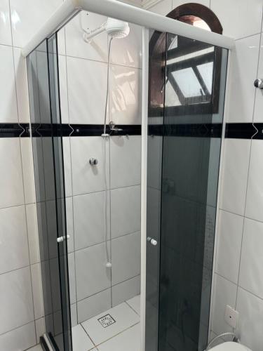 une douche avec une porte en verre à côté des toilettes dans l'établissement Cantinho do Aconchego, à São Lourenço