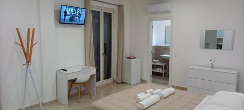 Habitación blanca con cama, escritorio y TV. en AMARE Bed & Breakfast en Rodi Garganico
