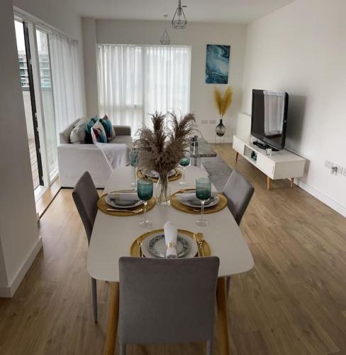 a living room with a table with chairs and a tv at Contemporary Urban Retreat, 2-Bedroom Haven by London City Airport in London