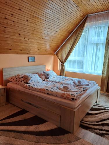 a bed in a bedroom with a wooden ceiling at Jázmin Apartman Zalakaros in Zalakaros