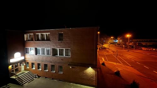 a large brick building at night with a street at Hotel Gifhorn INN in Gifhorn