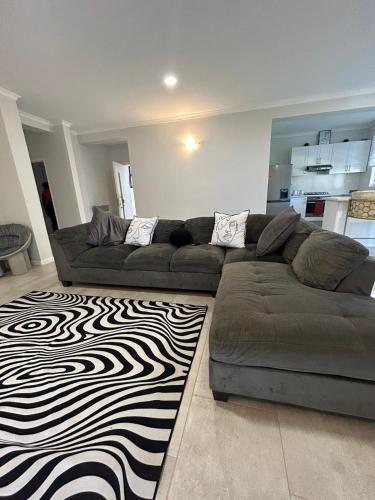 a living room with a couch and a black and white rug at Feels Like Home Condo Victoria Falls in Victoria Falls