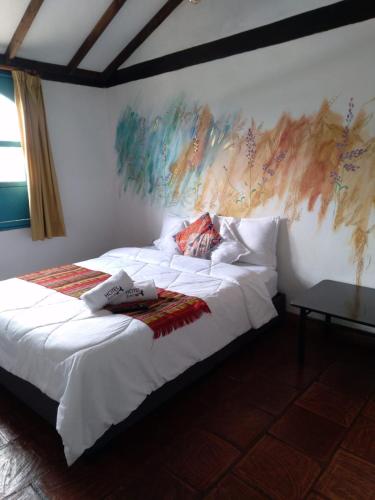 a bedroom with a bed with a painting on the wall at FLORA HOSPEDAJE in Suesca