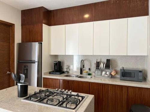 una cucina con armadi bianchi e piano cottura di Modern 3 bedroom Private home with Aircondition a Zapotlanejo