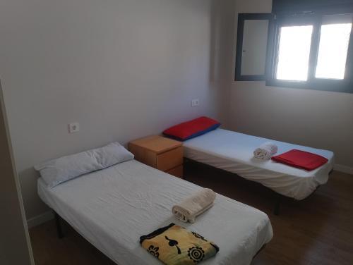 Habitación con 2 camas individuales y ventana. en Bajo con jardin en primera línea de playa, en Málaga