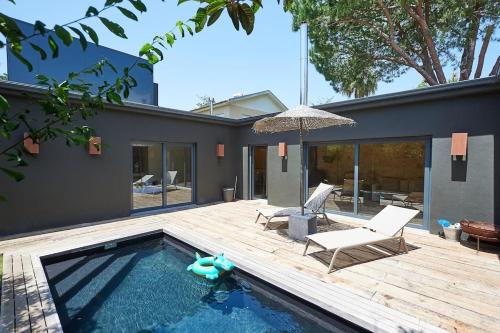 a backyard with a pool and a deck with a chair and an umbrella at Villa Oasis - w pool near Cascais centre in Cascais