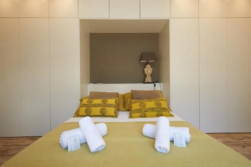 una camera da letto con un letto con lenzuola bianche e cuscini gialli di Villa Oasis - w pool near Cascais centre a Cascais