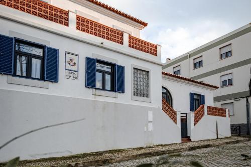 a white building with blue shutters on it at Casa do Músico in Alverca