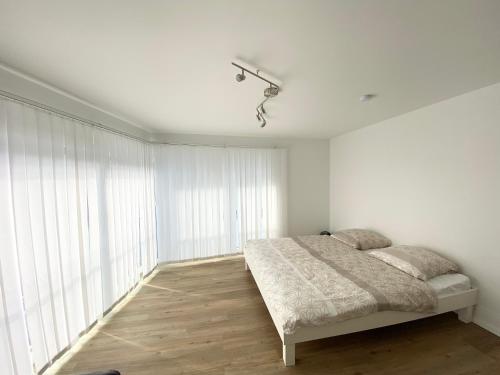 ein Schlafzimmer mit einem Bett und einem großen Fenster in der Unterkunft Modern One Bedroom + Bathroom Apartment, 10 min from Basel City in Grenzach-Wyhlen