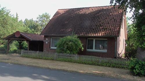 a brown house with a fence and aophe at Ferienhaus mit überdachter Terrasse und Carport in Walsrode