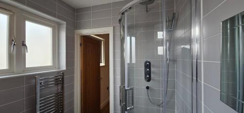 y baño con ducha y azulejos grises. en Modern Studio apartment in Town center en Ipswich