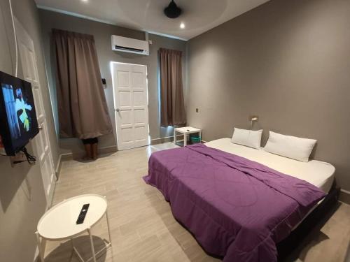 een slaapkamer met een groot bed en een paarse deken bij Kesuma Homestay Pantai Murni in Yan
