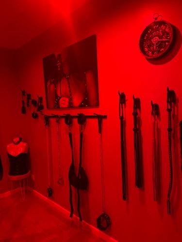 a red room with axes hanging on a wall at La Maison des Plaisirs Love room in Champigny-sur-Yonne