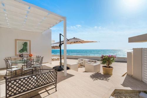 une terrasse avec une table et un parasol et l'océan dans l'établissement Ferienhaus für 6 Personen ca 100 qm in Cicirata, Sizilien Ostküste von Sizilien, à Avola