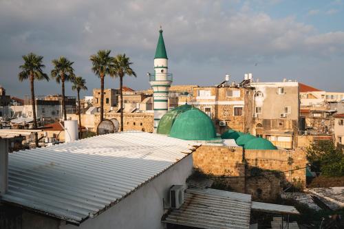a mosque with a green and white tower in a city at Villa Sera in ‘Akko