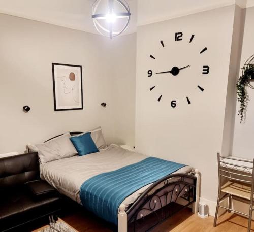 1 dormitorio con 1 cama y reloj en la pared en Stylish Apartment, self check-in, 25mins to Gatwick Airport, en Thornton Heath