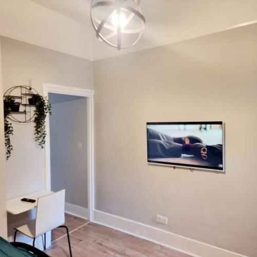 a living room with a tv on the wall at Stylish Apartment, self check-in, Ideal 4 Contractors, 25mins to Gatwick Airport in Thornton Heath