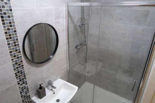 a bathroom with a shower and a sink and a mirror at Two-Bedroom Apartment with Scenic Balcony View in Shipley