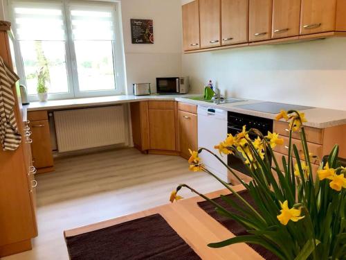 une cuisine avec des placards en bois et une table ornée de fleurs jaunes dans l'établissement Ferienwohnung „Landidylle“, à Stemwede