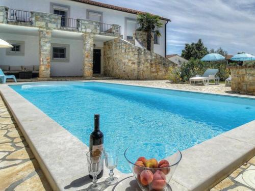 una bottiglia di vino e un cesto di frutta accanto alla piscina di Villa Palma a Linz