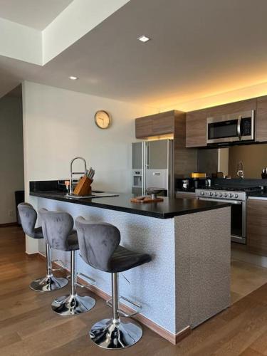 a kitchen with a counter with bar stools at Olivo&Laurel HP - Sur in Mexico City