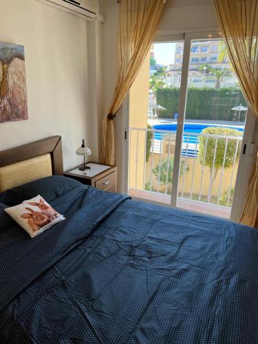 1 dormitorio con cama azul y ventana grande en First Line Cabo Roig Orihuela Costa, en Orihuela Costa