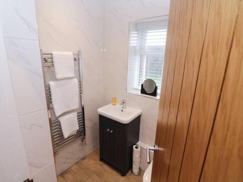 a white bathroom with a sink and a mirror at Ash Lodge in Ashbourne