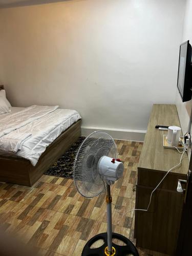a room with a fan and a bed at Close 5 in Garki