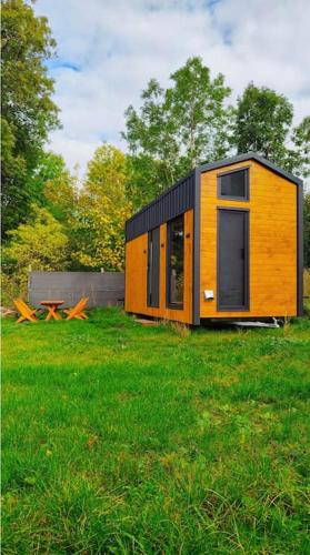 een klein huis in een grasveld bij Przytulny domek 150 m od jeziora in Charzykowy