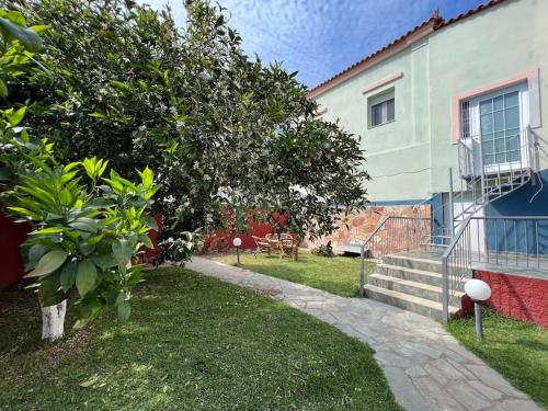 a house with a yard with a tree and stairs at Vasiliki's house in Amarinthos