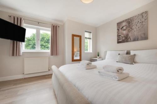 a white bedroom with a large bed with two towels on it at 3 Bed Holiday Home in Llandeilo with log burner in Llandeilo