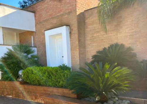 a brick house with a white door and some plants at Villa Marlene Casa vacanze in parco privato in Monterusciello