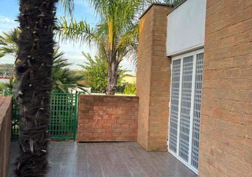 a building with a gate and a palm tree at Villa Marlene Casa vacanze in parco privato in Monterusciello