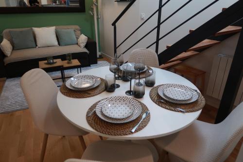 a white dining room table with chairs and a couch at Duplex cosy à 7 minutes à pied du RER Nanterre ville in Nanterre