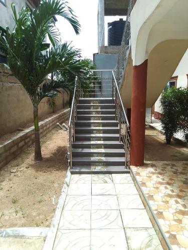 a staircase leading up to a building with a palm tree at Kim's Guest House in Kasoa