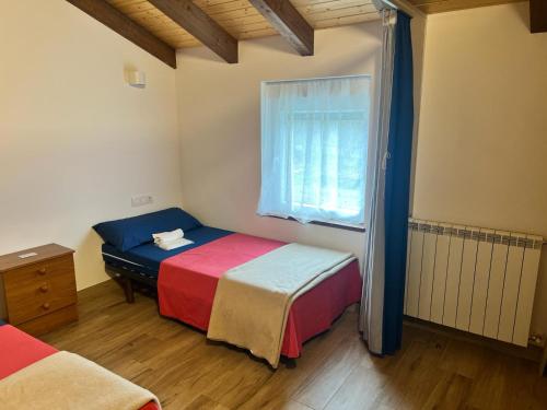 Un dormitorio pequeño con dos camas y una ventana. en Pensión KM73 CAMINO PRIMITIVO Ferreira - Lugo, en Palas de Rei 