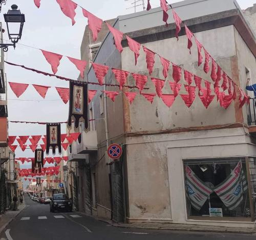 una calle con banderas rojas colgando sobre un edificio en CASA ROSINA, en SantʼAntìoco