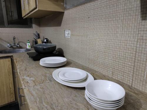 three white plates on a counter in a kitchen at Syedah 's Homestay in Lahore