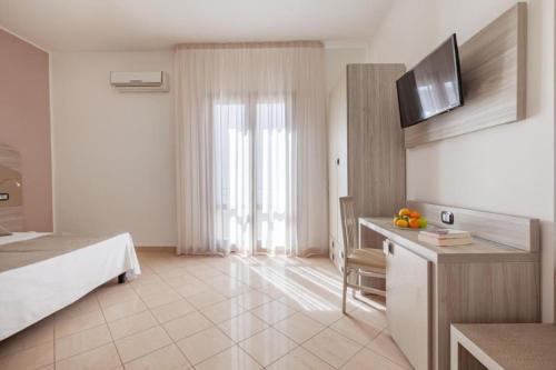 a hotel room with a bed and a desk with a television at La Conchiglia sul mare Hotel in San Vito lo Capo