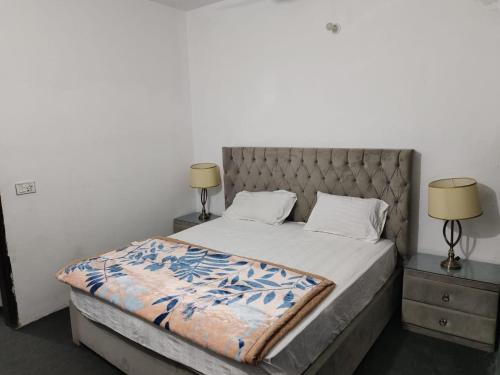 ein Schlafzimmer mit einem Bett mit zwei Nachttischen und zwei Lampen in der Unterkunft Syedah 's Homestay in Lahore