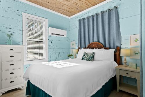 a blue bedroom with a bed and a window at Parrot Beach Cottages Suite #2 in Siesta Key