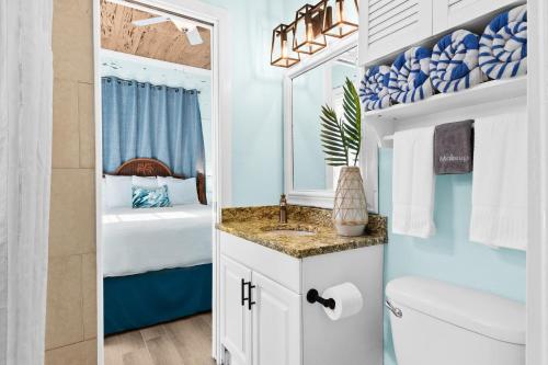 a bathroom with a sink and a toilet and a bed at Parrot Beach Cottages Suite #2 in Siesta Key