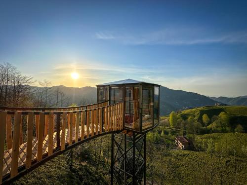 a wooden bridge over a hill with the sun in the background at Organic village bungalow in Ayder Yaylasi