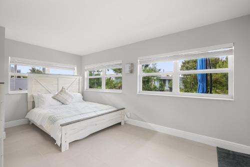 a white bedroom with a bed and two windows at 3/2 Close to Beach Pet Friendly in Fort Pierce