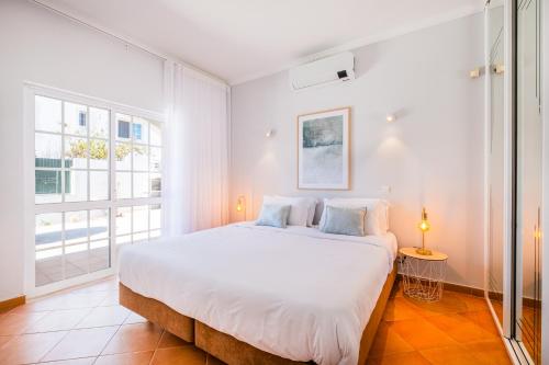 a white bedroom with a large bed and a window at Vicente Mar Luxury Villa - Private Pool in Albufeira