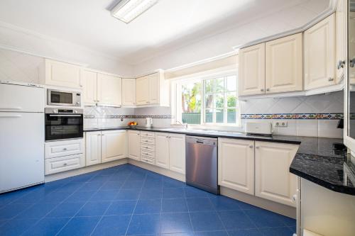 a kitchen with white cabinets and a blue tile floor at Vicente Mar Luxury Villa - Private Pool in Albufeira