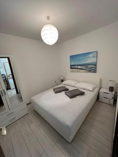 a white bedroom with a large white bed and a window at Apartment Irena in Jadranovo