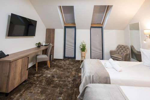 a hotel room with two beds and a desk and a tv at ALIVE HOTEL in Oradea